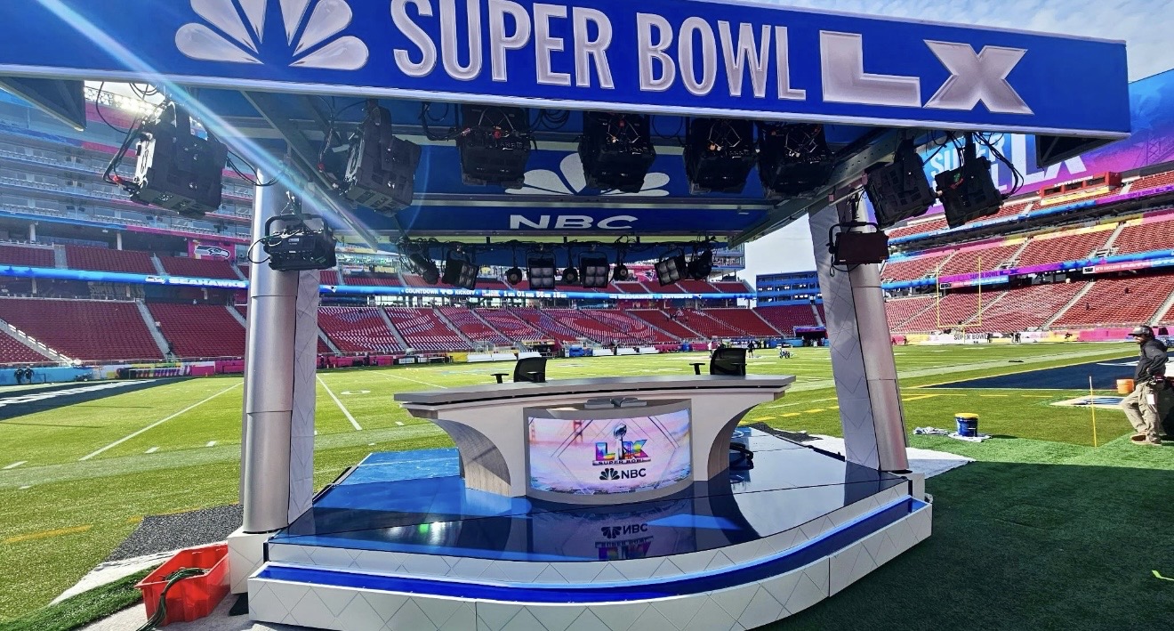 Printed broadcast desk and overhead header graphics on a stadium field