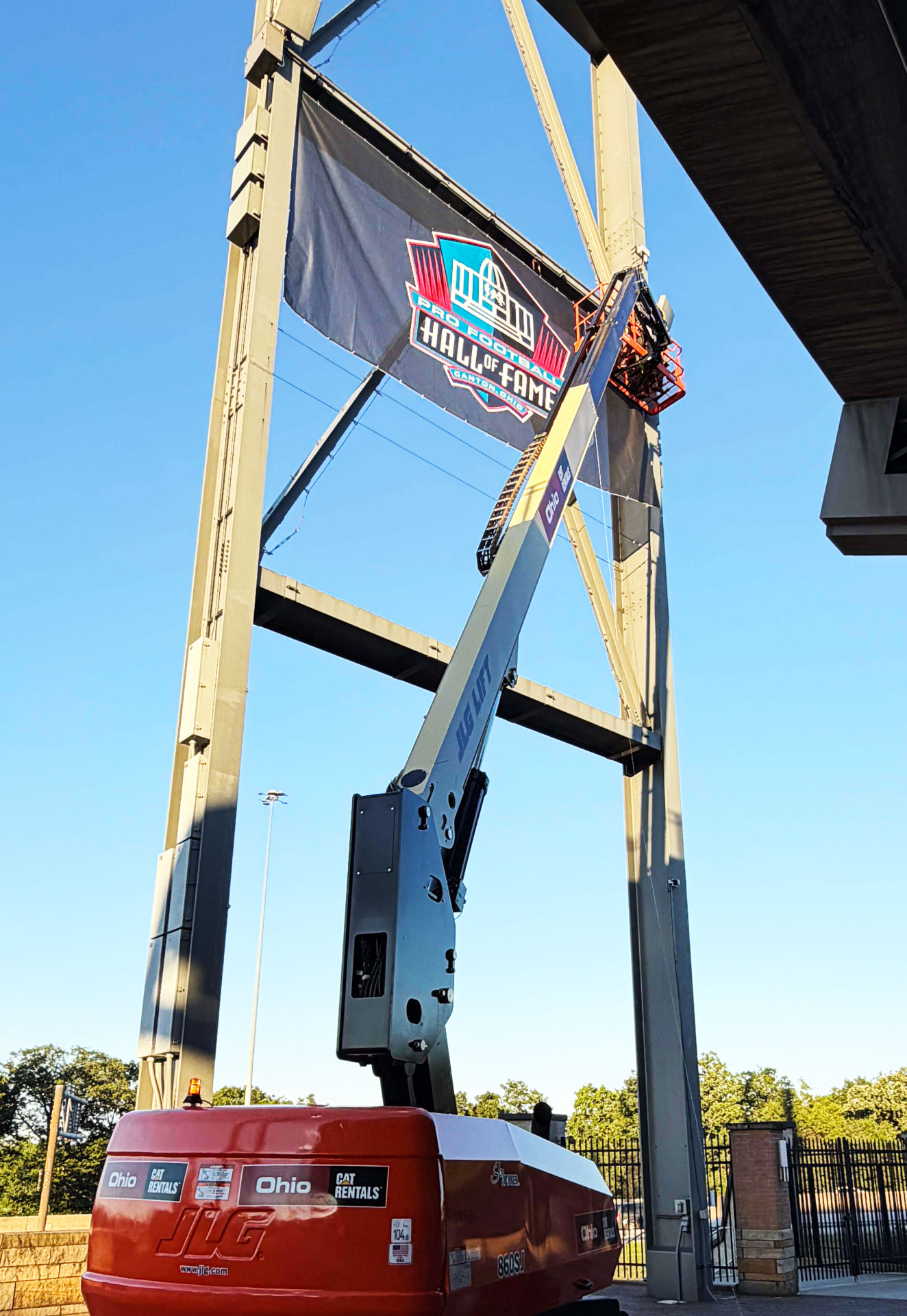 Boom lift raising an installer to a large banner high on a steel structure