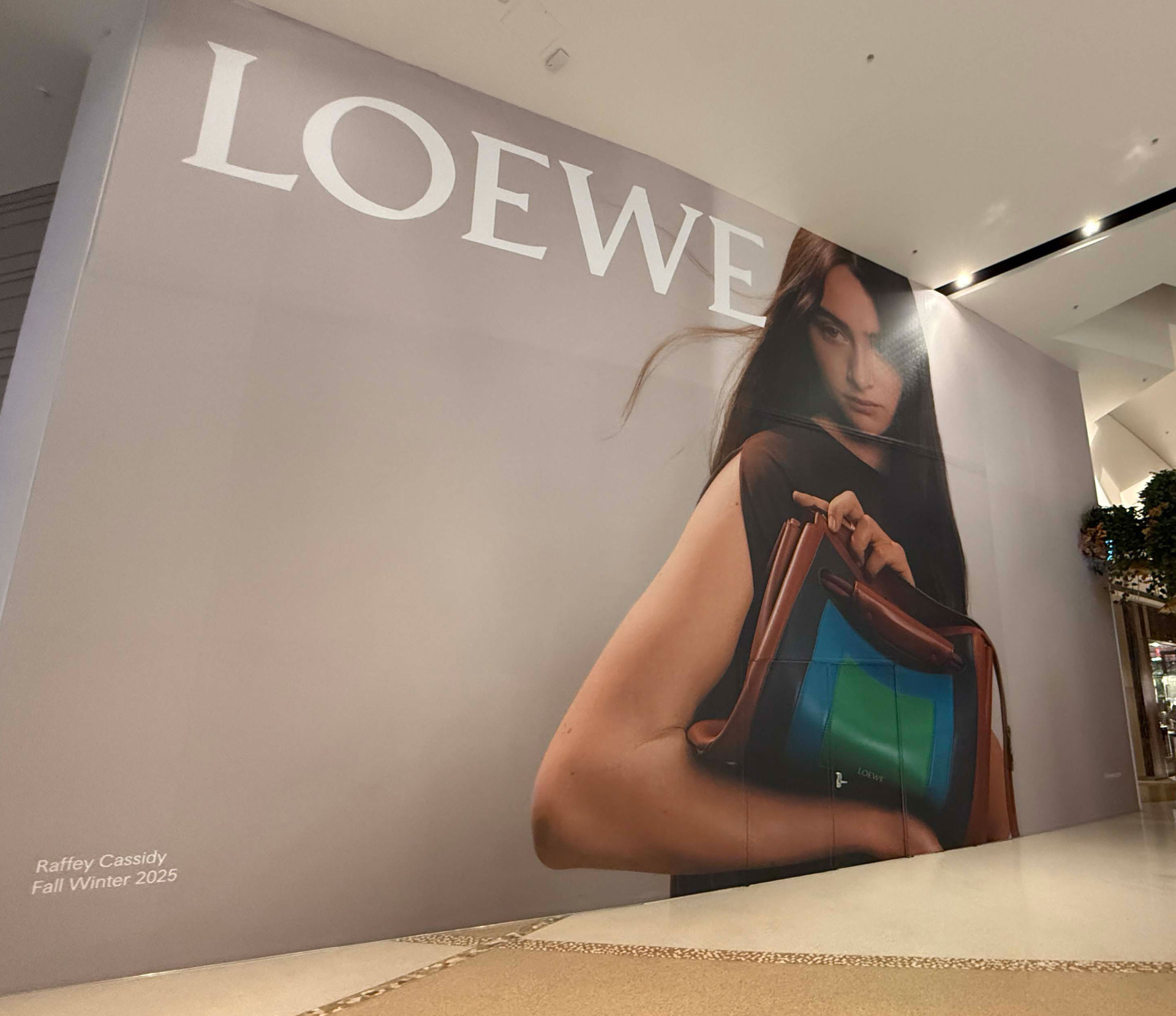 Floor-to-ceiling printed wall graphic of a fashion campaign inside a shopping centre