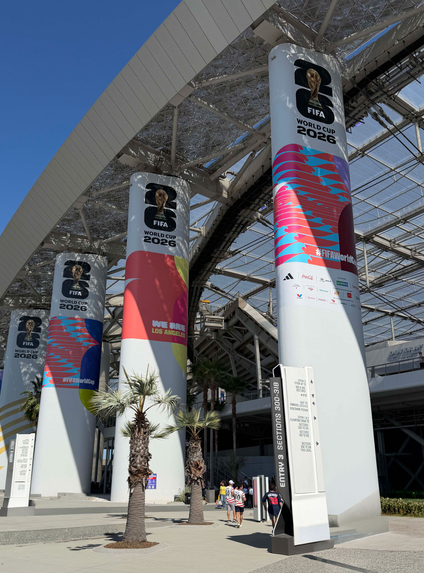 Stadium columns wrapped in large graphics with visitors walking below