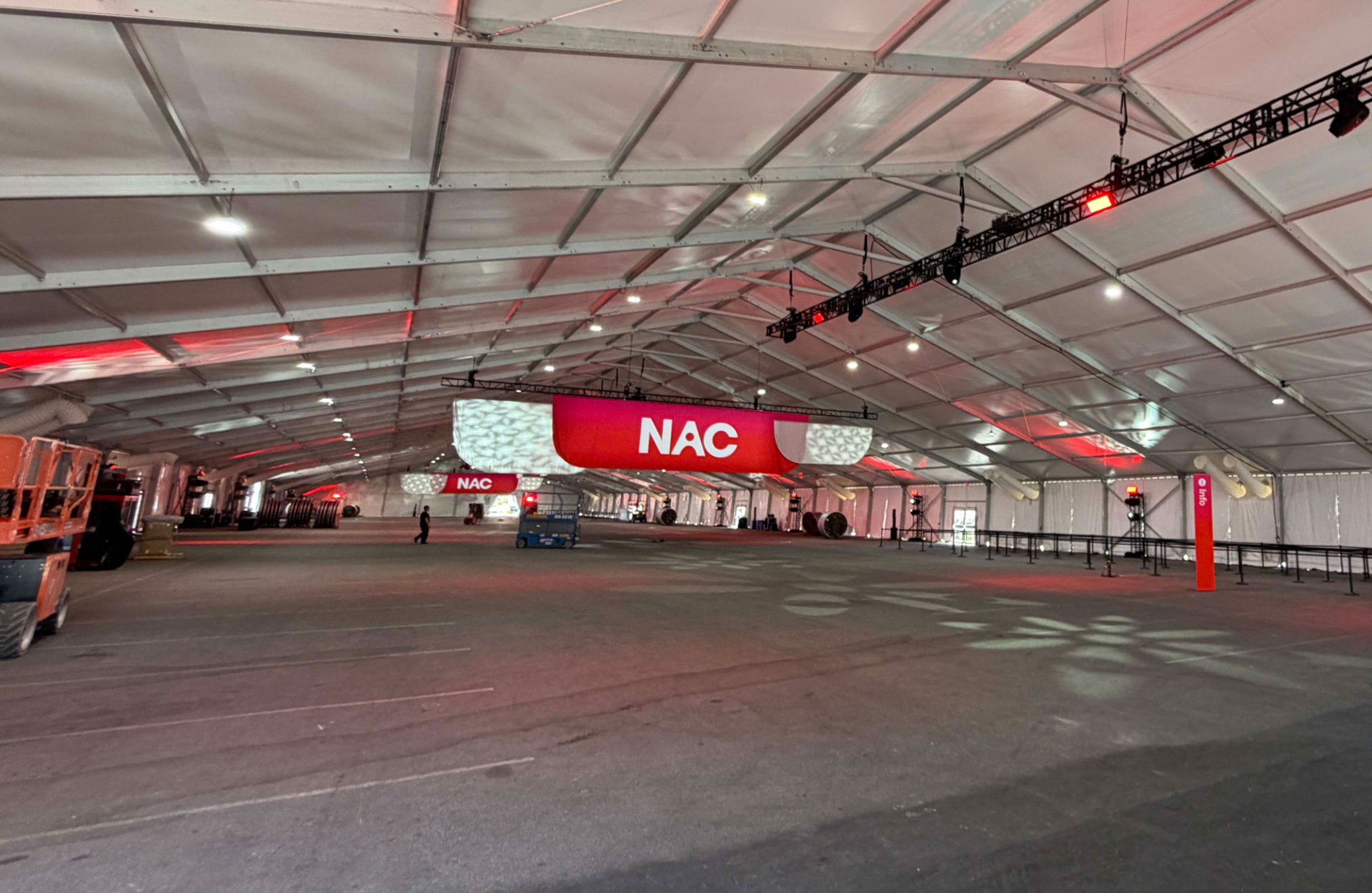 Large red NAC banners suspended from truss inside a vast event tent