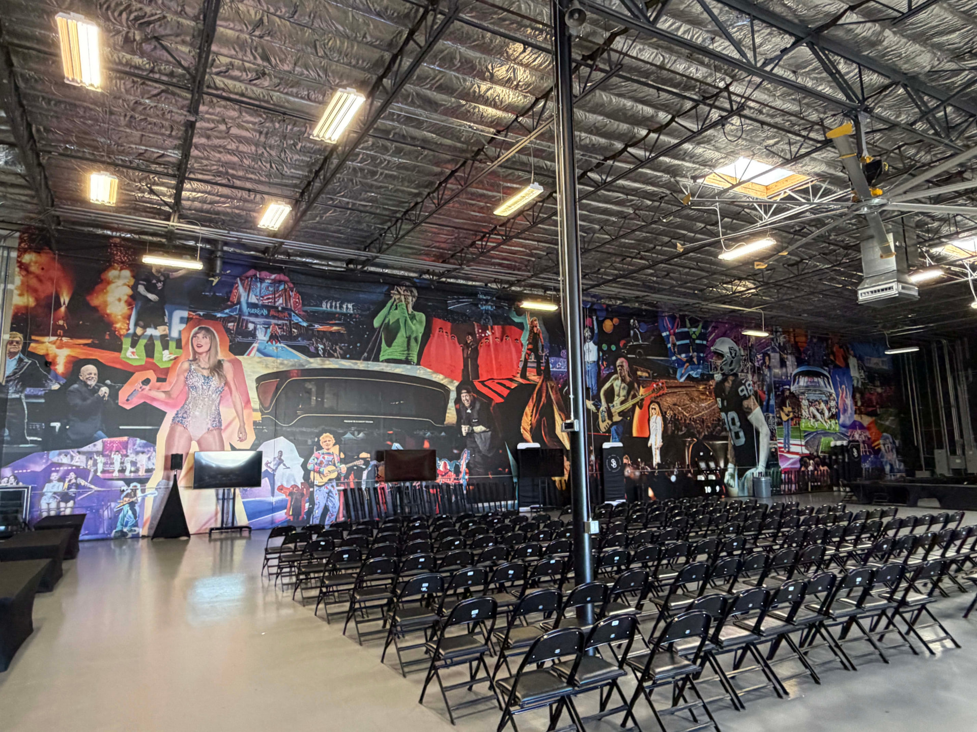 Large event hall with a full-wall printed mural behind rows of seating