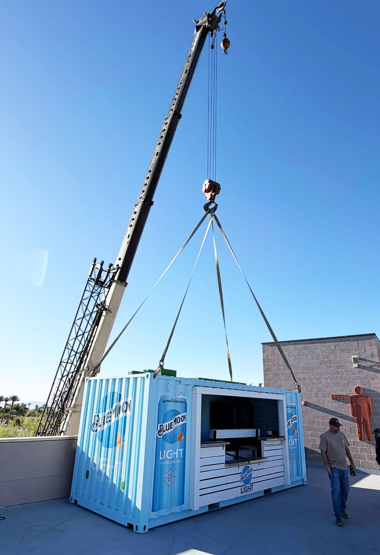 Crane lifting a branded container structure into place on a rooftop